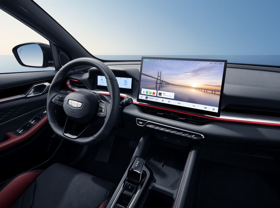 Interior de coche moderno con pantalla táctil, volante de cuero y elegantes detalles rojos.
