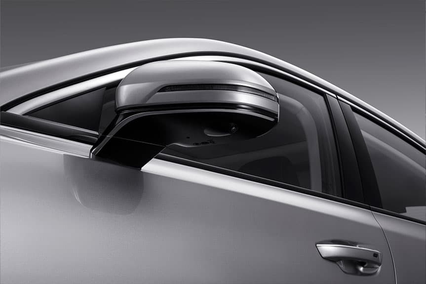 Espejo retrovisor lateral plateado de un coche con cámara integrada y luz de giro.