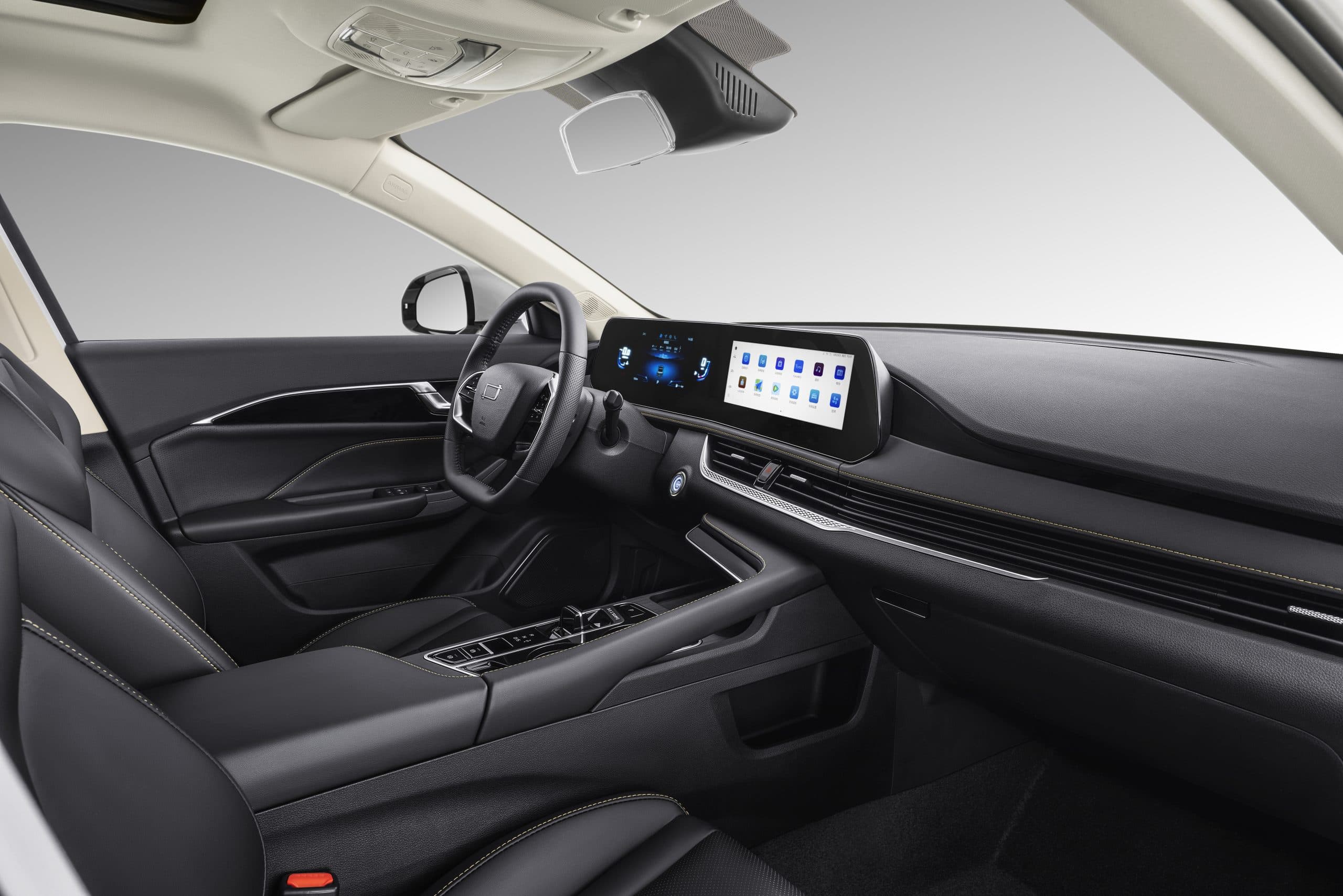 Interior de automóvil moderno con asientos de cuero negro, costuras amarillas y pantallas digitales.