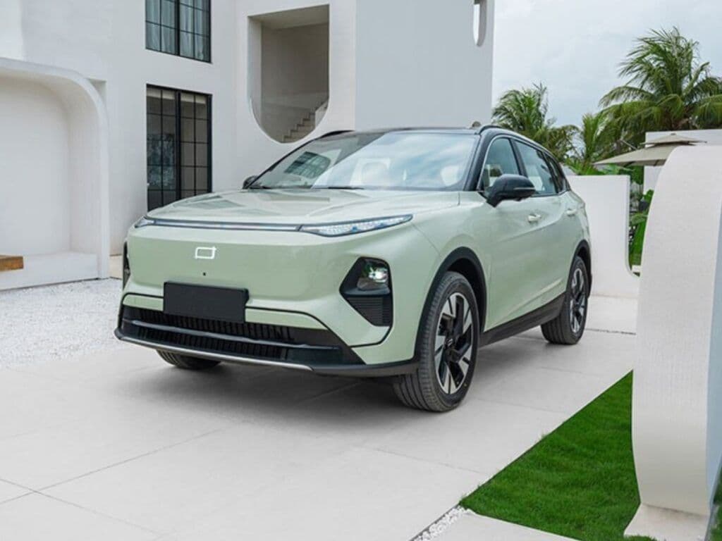 SUV eléctrico verde menta estacionado frente a una moderna casa blanca con arquitectura minimalista.