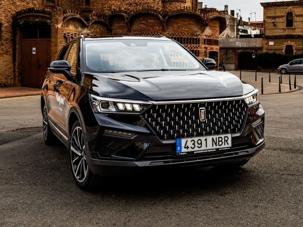 SUV negro con parrilla cromada estacionado en una calle frente a un edificio histórico.