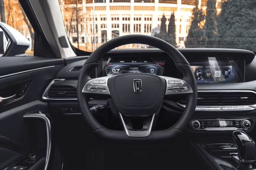 Vista interior de un coche moderno con volante de cuero y pantallas digitales avanzadas.